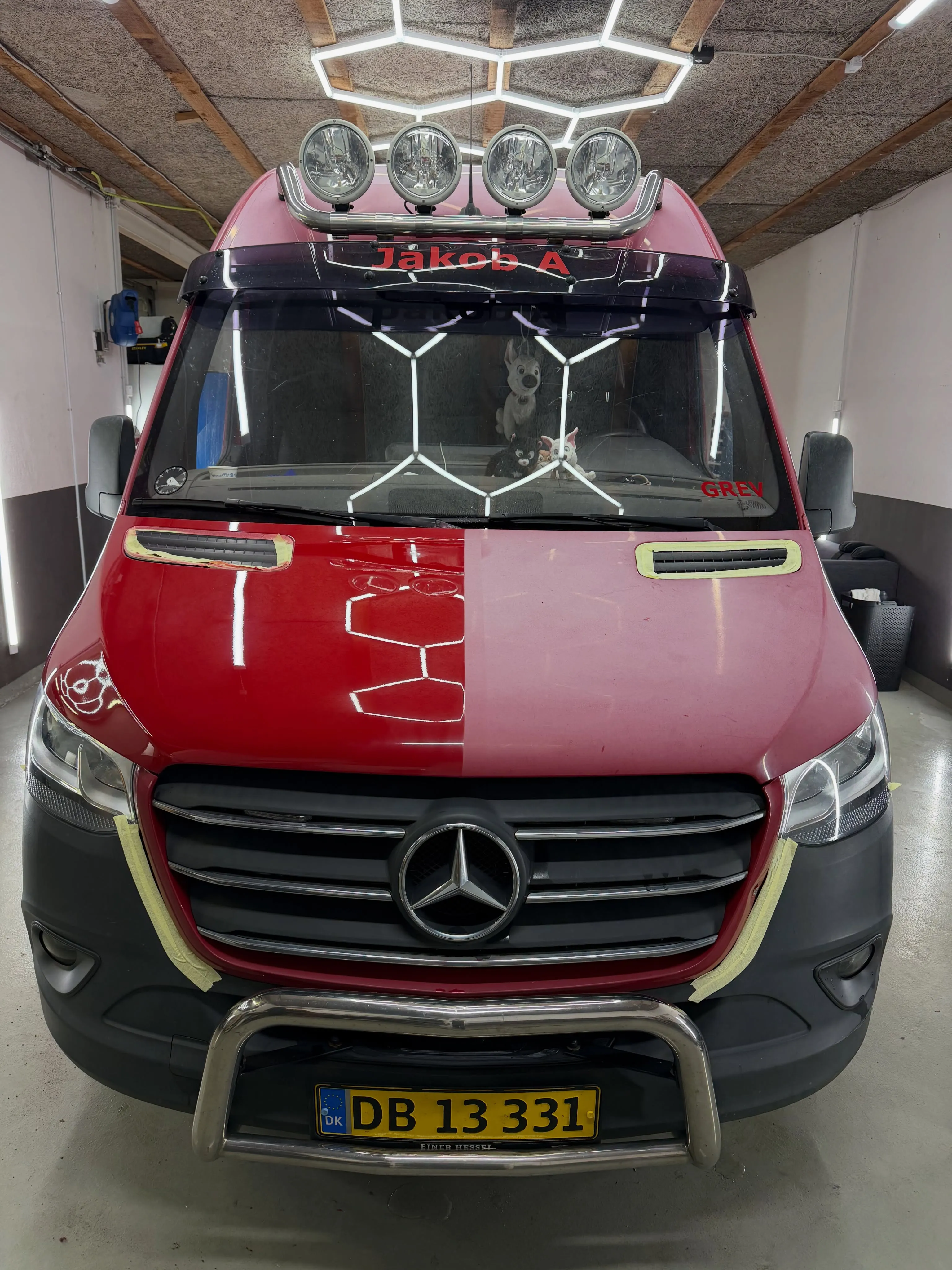 Rød Mercedes-Benz Sprinter set forfra i klargøringshal, motorhjelm delvis poleret med tydelig kontrast.